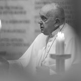 Ein schwarz-weiß-Bild, auf dem Papst Franziskus zwischen Kerzen zu sehen ist.