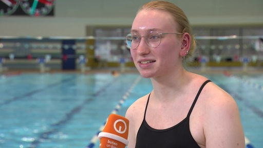 Die Bremer Para-Schwimmerin Anna Josephine Schulz sitzt am Beckenrand beim Interview.