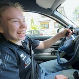 Eine junge Frau sitzt am Steuer ihres Autos.