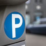 Auf einem Parkscheinautomat ist ein blauer Kreis mit weißem P zu sehen.