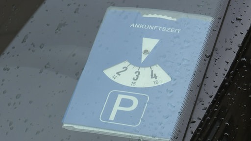 Eine Parkscheibe platziert unter der Windschutzscheibe eines Autos.