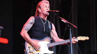 Peter Maffay steht während eines Konzerts auf einer Bühne.
