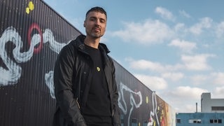 Mann, Ende 30, vor Graffiti