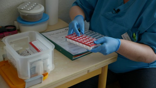 Eine ambulante Pflegerin teilt die Tabletten für Patienten in eine Box ein.