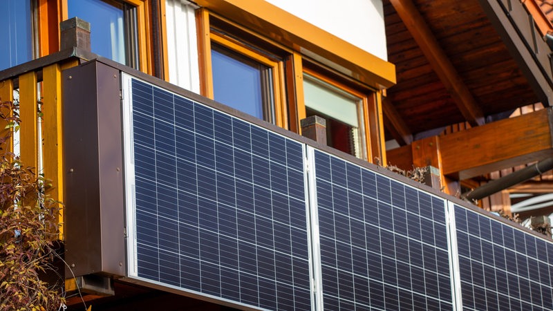 Am Balkon eines Einfamilienhauses ist eine Solaranlage angebaut.