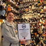 Eine Frau hält eine Urkunde in der Hand. Im Hintergrund stehen in einem Regal etliche Pinguin-Figuren.