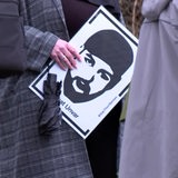 Eine Person hält ein Plakat mit einem Gesicht darauf.