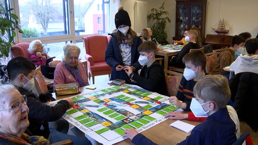 Kinder und ältere Menschen spielen zusammen ein Gesellschaftsspiel.