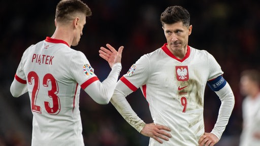 Die polnischen Nationalspieler Krzystof Piatek und Robert Lewandowski sprechen miteinander