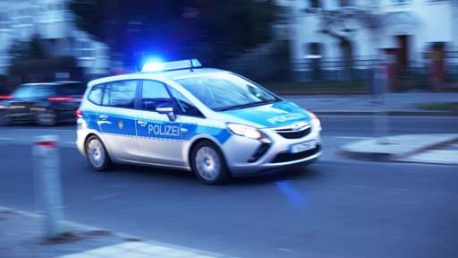 Ein Polizeiauto fährt mit Blaulicht über eine Straße