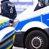 Ein Polizist steht zwischen Einsatzfahrzeugen
