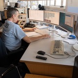 Ein Mann in Polizei-Uniform sitzt an einem Schreibtisch.