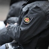 Polizisten im Einsatz bei einer Demonstration, Regentropfen sind auf den Uniformjacken zu sehen, die Helme sind in den Händen.