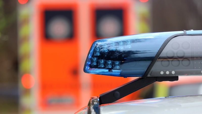 Ein Blaulicht auf einem Polizeiauto, im Hintergrund ein Rettungswagen