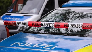 Polizeifahrzeuge hinter Polizeiabsperrband mit Aufschrift "Polizeiabsperrung"