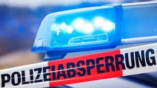 Ein Band mit der Aufschrift "Polizeiabsperrung" vor einem Blaulicht