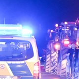 Ein Polizeifahrzeug mit Blaulicht zwischen Traktoren auf einer Autobahn (Symbolbild)