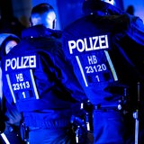 Polizisten in schwarzen AnEinsatzanzügen stehen im dunkeln nebeneinander