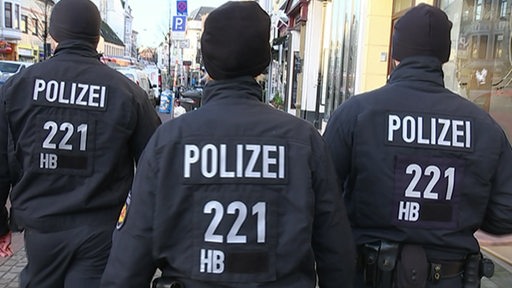 Drei Polizeibeamte laufen durch das Viertel.