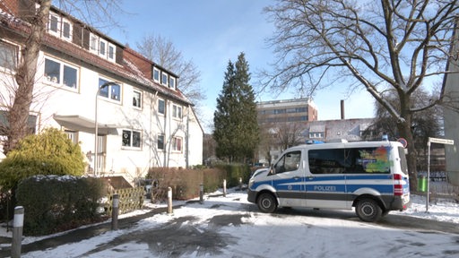 Ein Polizeiwagen steht auf einem Parkplatz in einem Wohngebiet.