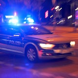 Ein Polizeiauto fährt mit Blaulicht im Dunkeln durch die Stadt.
