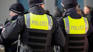 Zwei Polizisten in voller Montur von hinten zu sehen