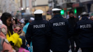 Polizisten patrouillieren am Rande eines Karnevalsumzugs.
