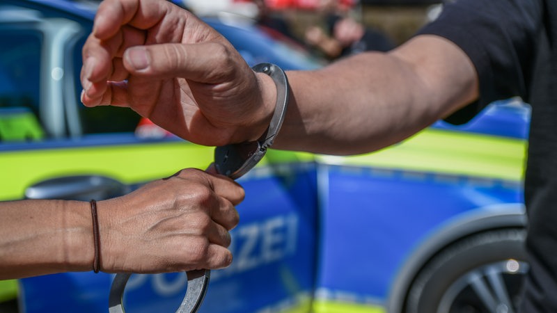 Polizist nimmt Mann in Handschellen fest