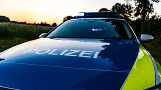 Ein Streifenwagen der Polizei mit Blaulicht und Schriftzug auf der Motorhaube.