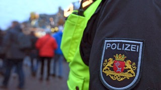 Bremer Polizei-Emblem am Ärmel, im Hintergrund verschwommen Menschen