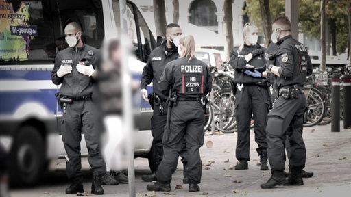 Ein paar Polizisten und Polizistinnen vor ihrem Auto in Bremen. 