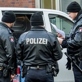 Drei Polizisten kontrollieren einen Autofahrer