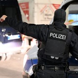 Polizisten stehen im Rahmen einer groß angelegten Razzia vor einem Haus. 
