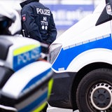 Ein Polizist steht zwischen Einsatzfahrzeugen.