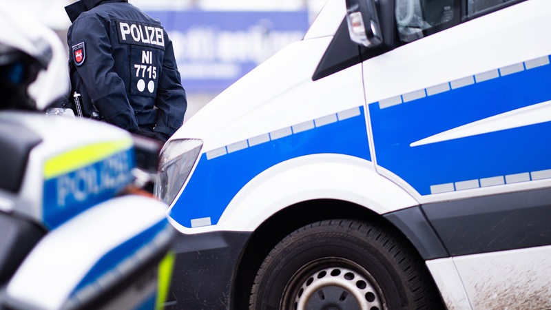 Ein Polizist steht zwischen Einsatzfahrzeugen.