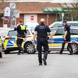 Die Polizei sperrt die Friedrichstraße in Nienburg. Zu sehen sind drei Polizisten, zwei Polizeiautos und ein rot-weißes Absperrband.