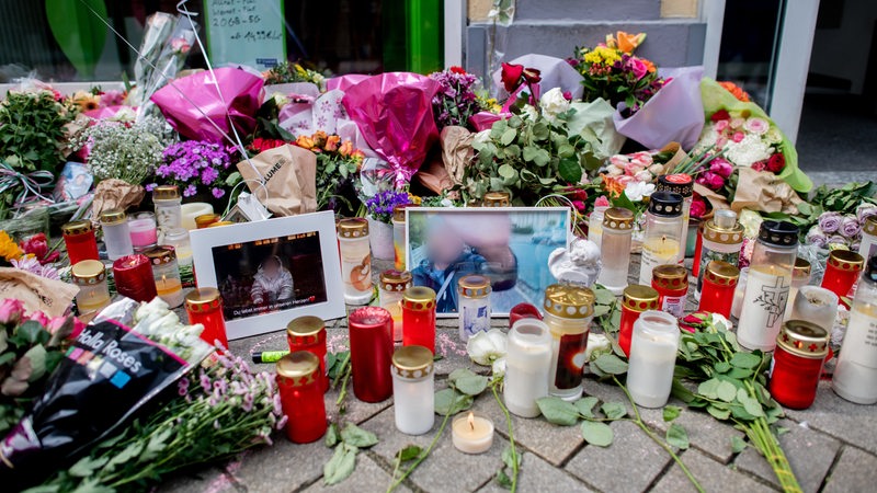 Zahlreiche Blumen und Kerzen stehen in der Innenstadt an einer Hauswand in der Achternstraße, in der am frühen Sonntagmorgen ein Mensch von Schüssen aus einer Polizeiwaffe tödlich verletzt wurde.
