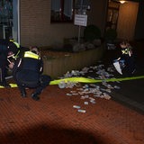 Polizisten aus Stade sammeln nach der Sprengung eines Geldautomaten vor der Filiale liegendes Bargeld ein.