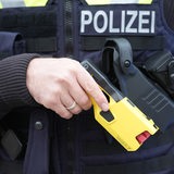 Ein Polizist hält einen Taser in seiner Hand