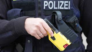 Ein Polizist hält einen Taser in seiner Hand