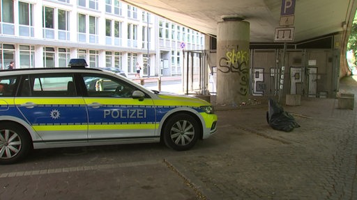 Ein Polizeiwagen steht unter einer Brücke. 