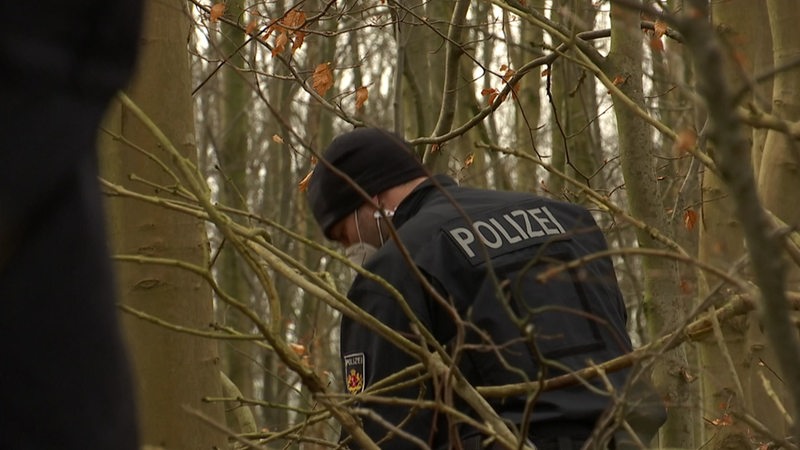 Ein Polizist im Wald am Suchen nach etwas.