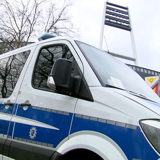 Ein Polizeiauto steht vor dem Weser-Stadion. Im Hintergrund sind die Flutlichtmasten des Stadions zu sehen