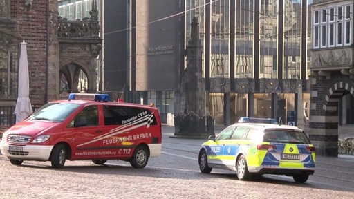 Jeweils ein Einsatzwagen der Polizei und der Feuerwehr Bremen stehen auf dem Marktplatz der Bremer Innenstadt.