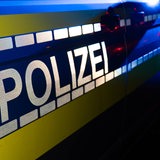 Auf einer Seitentür eines Autos steht "Polizei". In der Dunkelheit ist noch Blaulicht zu sehen.