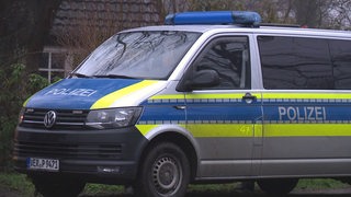 Ein Polizeiwagen vor einem alten Bauernhaus.