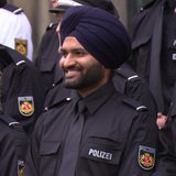 Ein Polizist mit einem Turban steht in einer Gruppe mit anderen Polizisten.