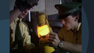 Zwei Polizisten halten eine gelbe Öllampe.