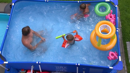 Eine Aufnahme eines Pools, in dem ein Mann und zwei Kinder schwimmen.
