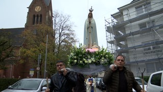 Männer tragen die Statue der Fatima durch Bremerhaven.